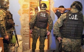 Efectivos de la TOE custodian a uno de los detenidos tras los allanamientos de esta ma&ntilde;ana. Foto: M. de Seguridad de Sta Fe