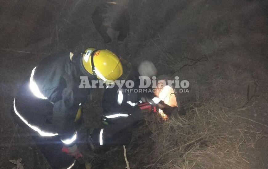 Bomberos trabajando. La dotación junto a una de las proteccionistas de Fighiera haciendo lo posible para rescatar al can.