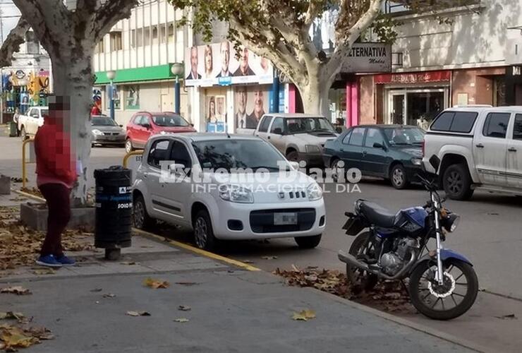 Los dos en infracción. No solo la moto está mal estacionada sino que el auto de la imagen está en línea amarilla.